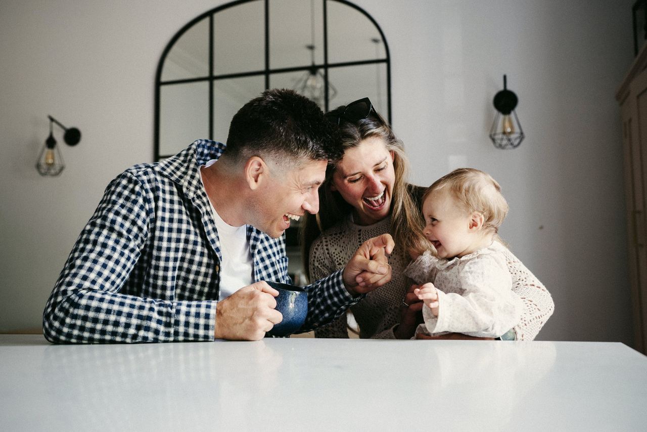 Siôn, Victoria and Margot laughing together at the kitchen table