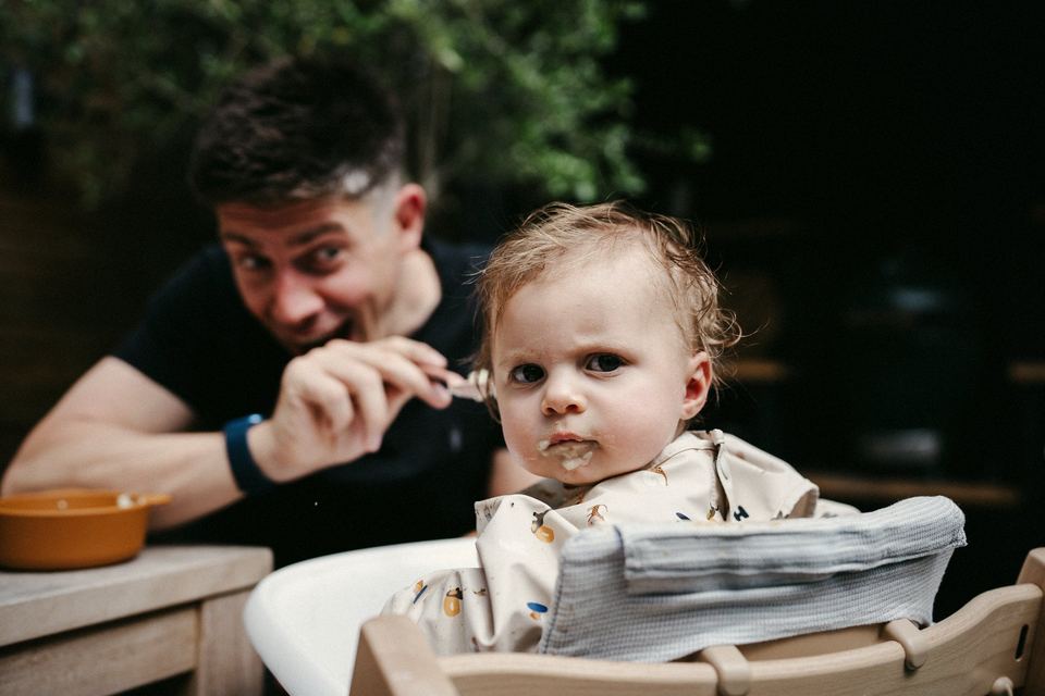 Siôn pulling a face while feeding Margot, who is unimpressed