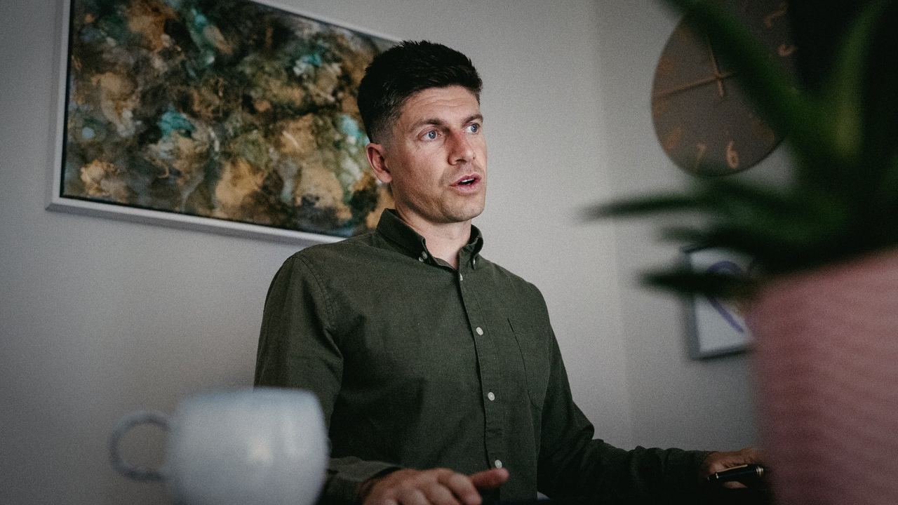 Siôn mid-conversation at his desk