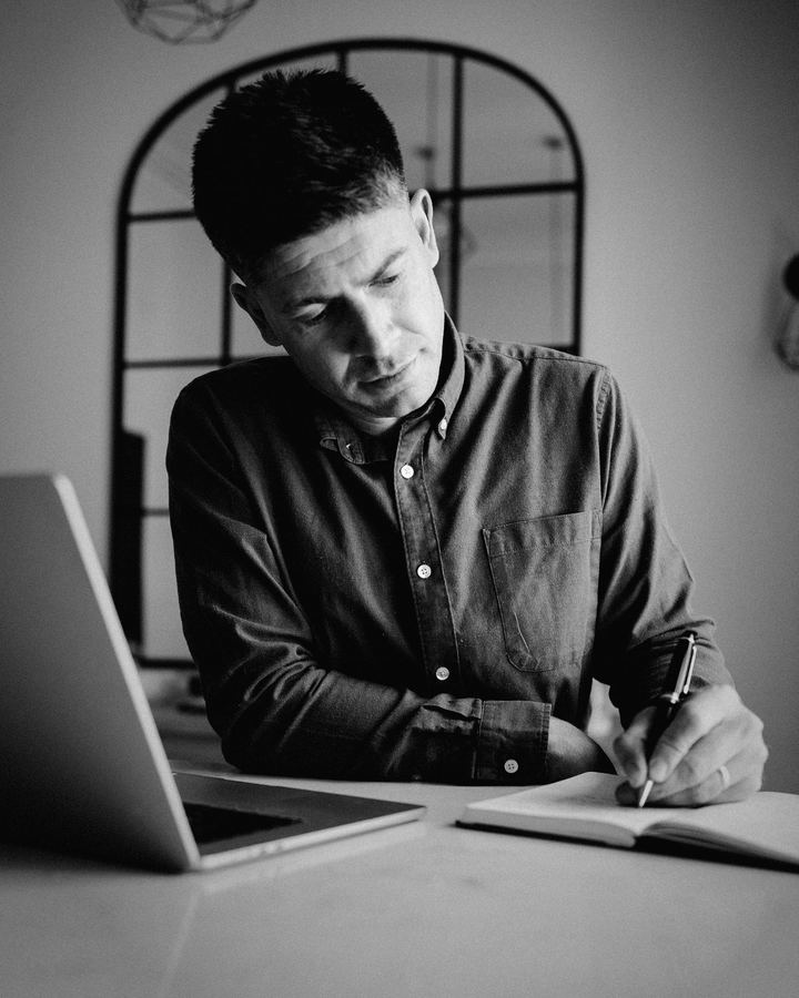 Siôn writing in a notebook, black and white